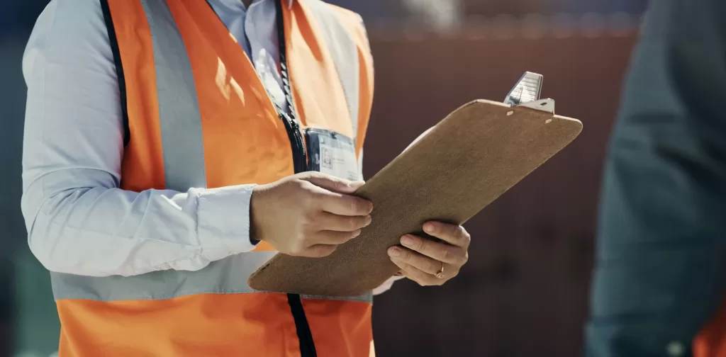Construction manager holding clipboard in orange vest